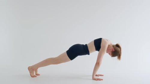 Junge Frau praktiziert Vinyasa Flow Yoga im minimalistischen Studio
