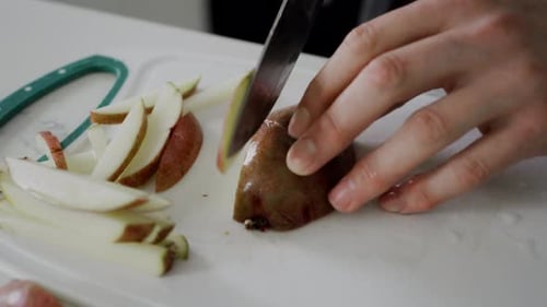 Cutting fresh potatoes on kitchen table counter for making french fries.