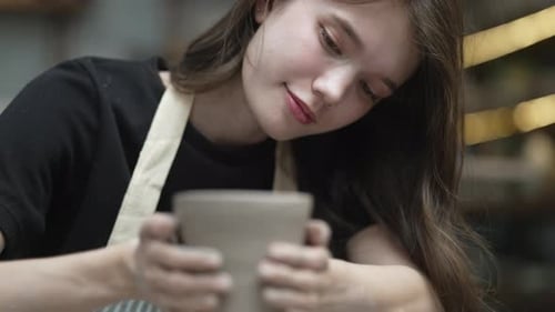 Young women is making earthenware at workshop.