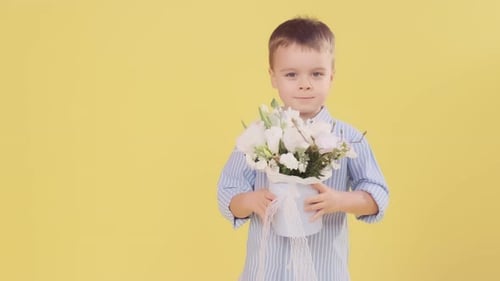 Young Boy Smelling Flowers and Smiling