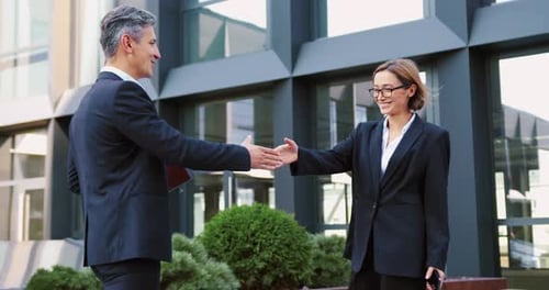 Businessman and Businesswoman Handshake in Front of Modern Office Building Corporate Meeting