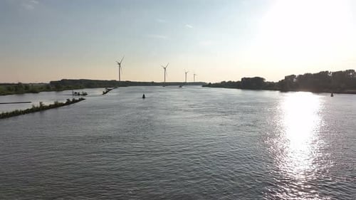 Wide River with Wind Turbines on Sunny Day