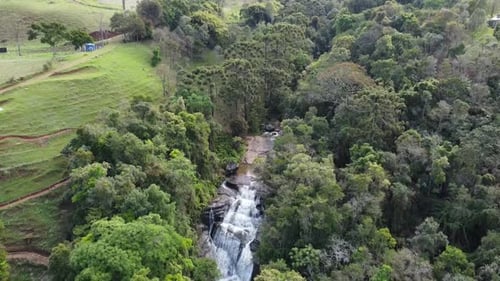 Drone camera movement downwards revealing a beautiful waterfall in the middle of the forest