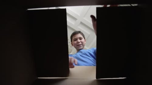 Niño sorprendido abriendo caja de cartón