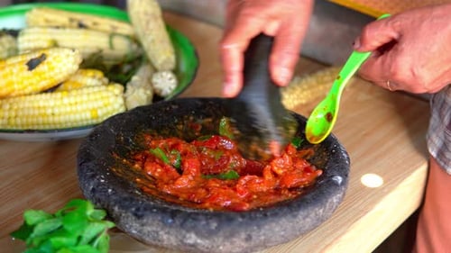 Eine Frau bereitet traditionellen indonesischen Sambal mit einem Steinmörser zu