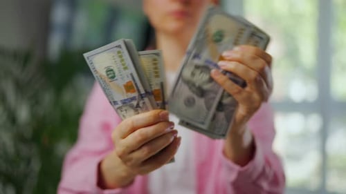 Woman Holds and Counts Stacks of US Currency
