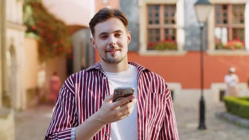 Happy Man Using Smartphone in European City