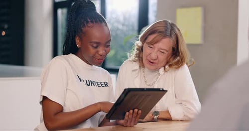 Two Women Laughing Using a Tablet Indoors