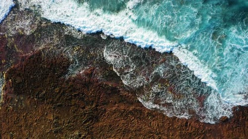 Ozeanwasser spült vulkanischen Felsen, raue Strandwellen krachen auf Küstenfelsen und machen Weiß