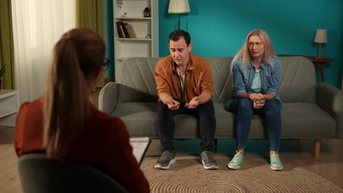 Un hombre ofendido se queja a un terapeuta sobre su esposa durante una sesión de terapia familiar El hombre