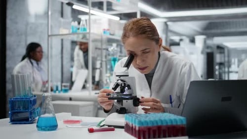 Woman Scientist Working with Microscope in Laboratory