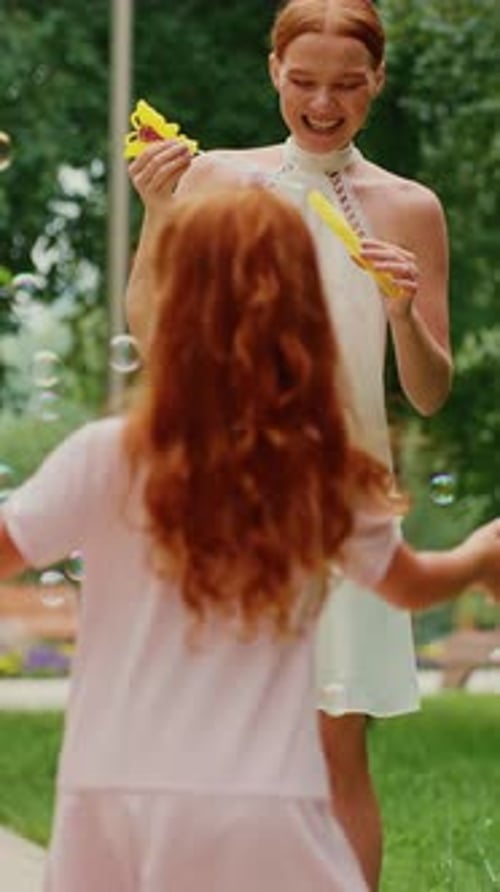 Mother and Daughter Playing with Bubbles in a Park on a Sunny Afternoon