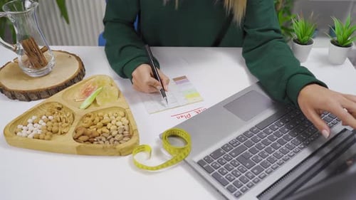 The woman is preparing a diet list by looking at the internet at home.