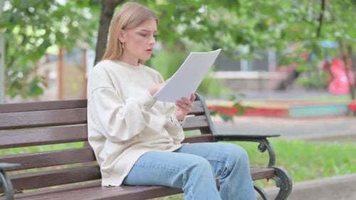 Woman Reading Papers Outside on Park Bench