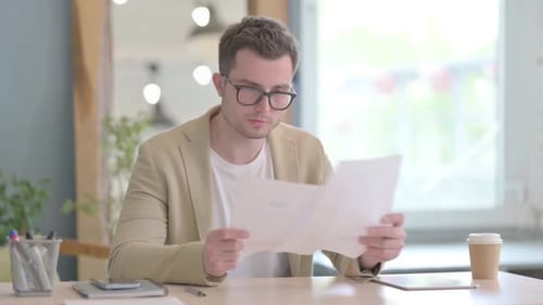 Man Reads Paperwork Then Celebrates at Desk