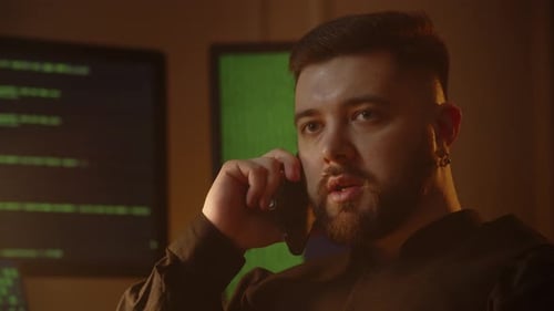 An Employee of an IT Company is Sitting in His Office and Talking on the Phone A Male Programmer