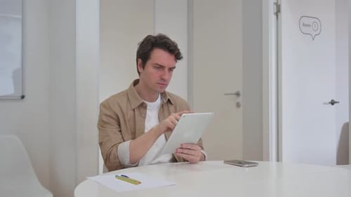 Young Adult Using Tablet at Office Table