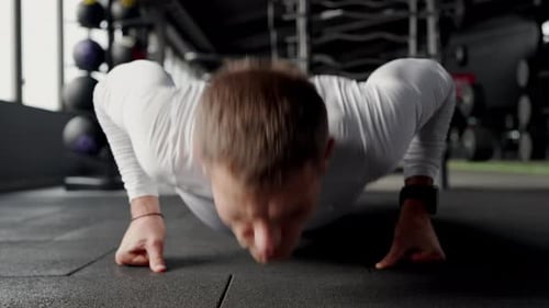 Focused Young Man Performing PushUps in a Modern Gym