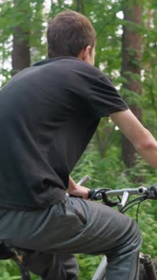 Young Boy Riding Bicycle Along Forest Path with Blurred Cyclist in Distance