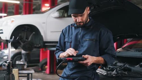 Electronics adjustment, with digital tablet. Mechanic working in a car service station.