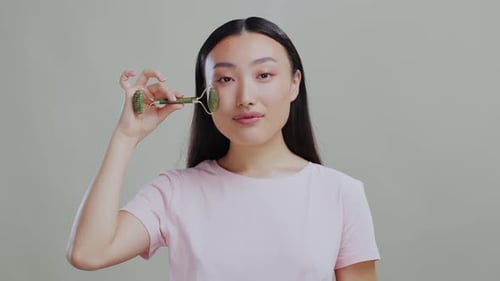 Young Woman Massaging Face with Jade Facial Roller
