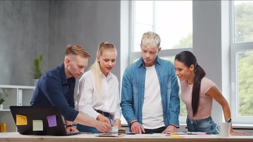 Team of Young Startupers is Working at the Table in the Office Discussing the Strategy and