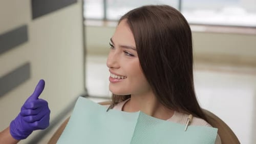 Woman is happy with results after oral hygiene and teeth whitening at dentist office.