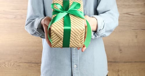 Person Holds Out A Wrapped Present With Green Bow