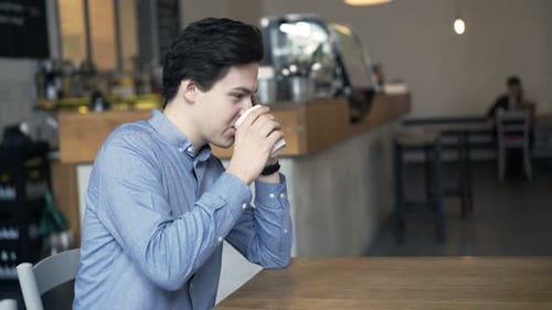 Young Teenager Talking on Cellphone and Drinking Coffee in Cafe Adolescent