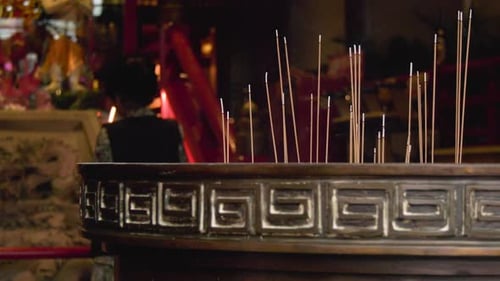Incense sticks burning in a temple and a lady praying in the background, Chinatown, Singapore.