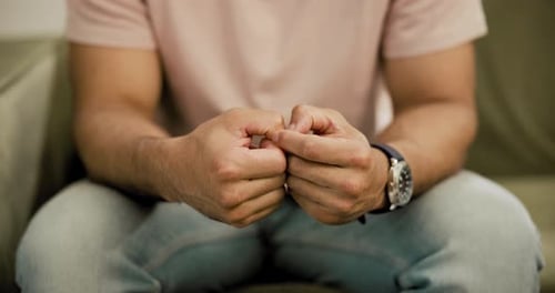 Hands, anxiety and a nervous person on a sofa in the living room of his home with stress