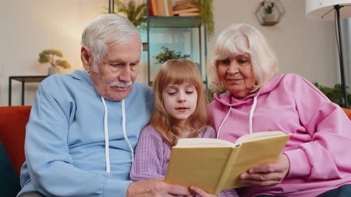 Grandparents reading a book with their granddaughter