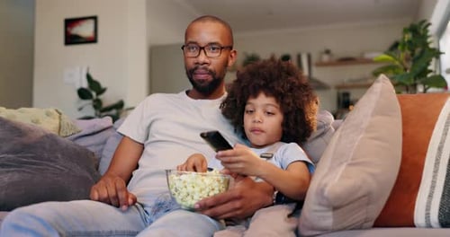 Father and Child Watching TV With Popcorn at Home