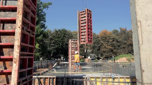 Ouvrier du bâtiment guidant des panneaux de coffrage sur un chantier de construction Un ouvrier du bâtiment en équipement de sécurité