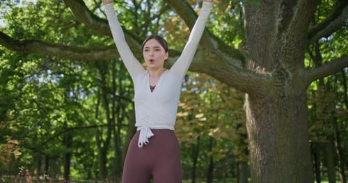 Young Beautiful Athletic Woman in Sportswear Doing Stretching and Warming Up in the Park Near a Tree