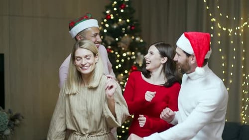 Friends Dancing in Santa Hats at Christmas Party