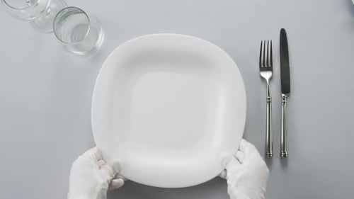 White-Gloved Hands Place Empty Plate on Table