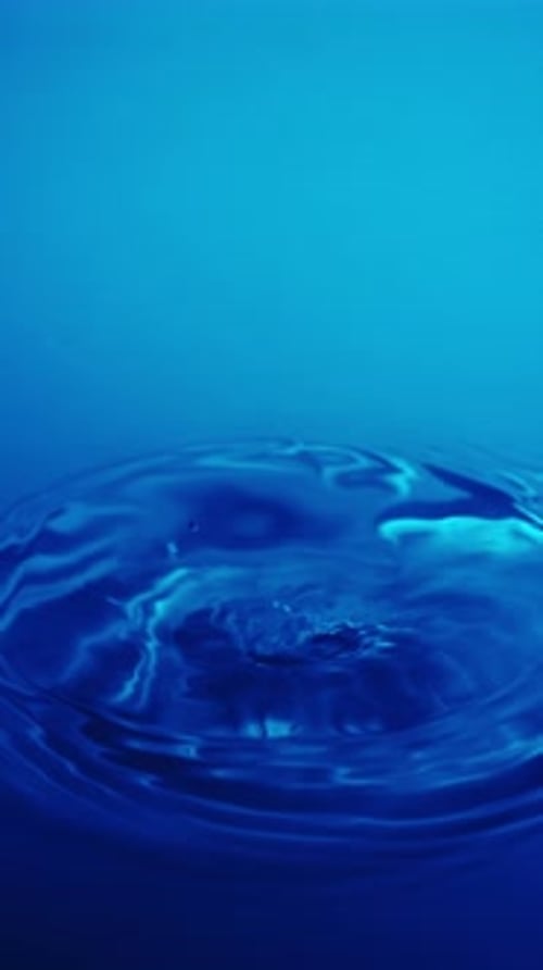 Water Drop Impacting Blue Liquid Surface