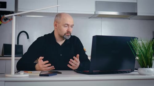 Bearded Man Video Conferencing at Home on Laptop