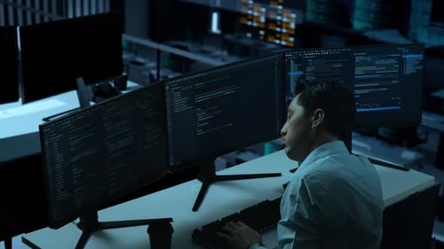 Side View Of Bored Asian Man Write Code With Multiple Computer Screens In office