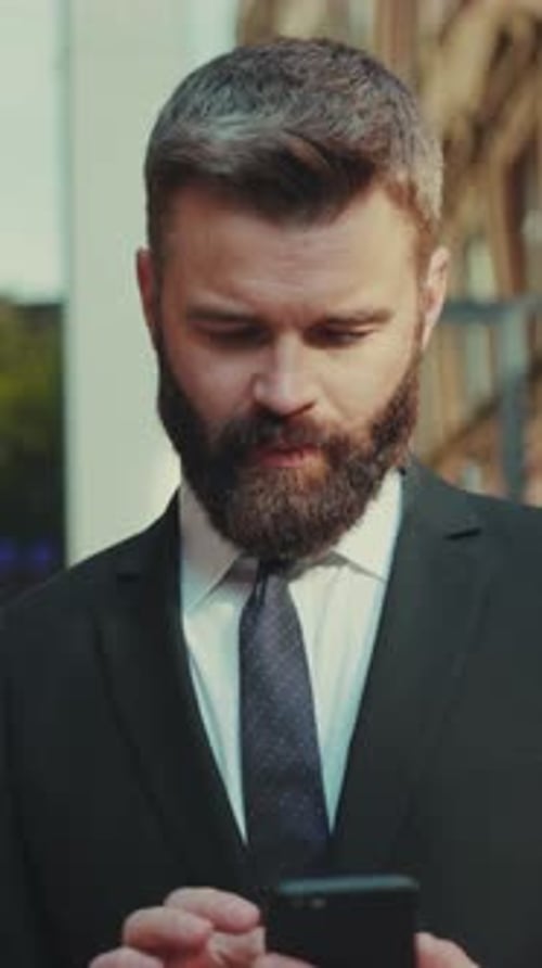 Successful Business Man Uses Smartphone and Go on the Big City Business District Street Smile Happy