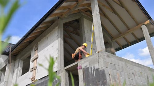 Builder Using Level on Unfinished Building Under Blue Sky