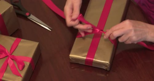 Hands Tie Pink Ribbon on Birthday Gift