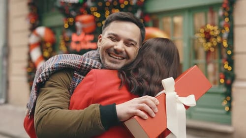 Couple Exchanging Gifts and Hugging at Christmas