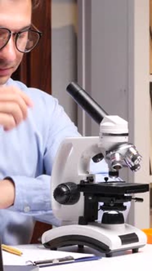Man Using Microscope in Brightly Lit Laboratory