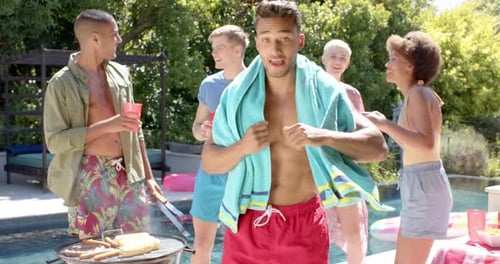 Portrait of happy diverse group of friends drinking drinks and dancing at pool party in summer