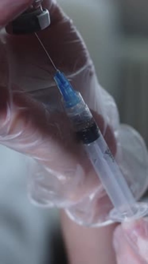 The Doctor Draws the Solution Into the Syringe Through the