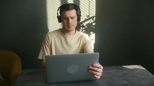 Man Working At Laptop With Headphones Indoors