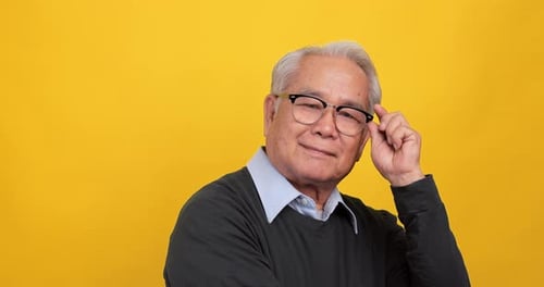 Close up, portrait of older man smiling and looking at the camera, isolated on yellow background