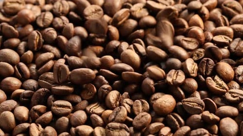 Roasted coffee beans falling in a pile close-up